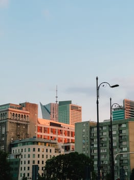 Warsaw skyline blending historic and contemporary architecture, silhouetted against warm sunset colors, revealing urban layering and contrasting building styles. Modern and historic buildings photo