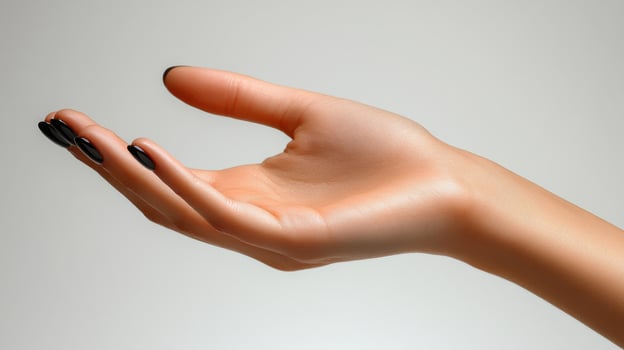 A hand with a black manicured nail is reaching out photo