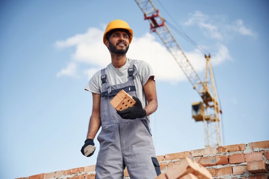 Working, against blue sky. Handsome Indian man is on the construction site photo