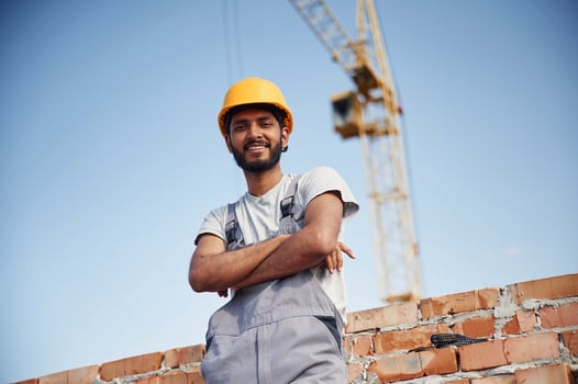 Standing with arms crossed.. Handsome Indian man is on the construction site photo