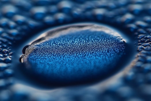 A close-up shot of a water droplet on a blue surface, showcasing a mesmerizing array of tiny bubbles. photo