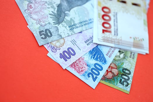 Argentine money in big amount lies on red color table photo