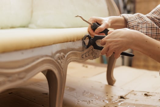 Hands removing staples from antique furniture during upholstery repair in workshop. photo