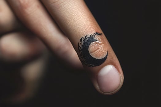 Crescent moon tattoo on finger symbolizing mystery and dreams photo