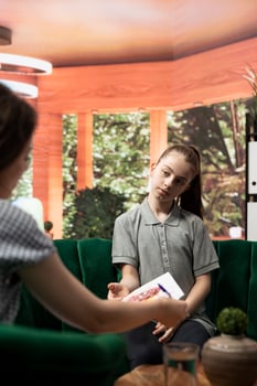 Therapist studies ominous gory drawings from a troubled teen, doing a psychoanalysis at therapy session. The dark sketches depict disturbing violent behavior, unsettling danger signs. photo