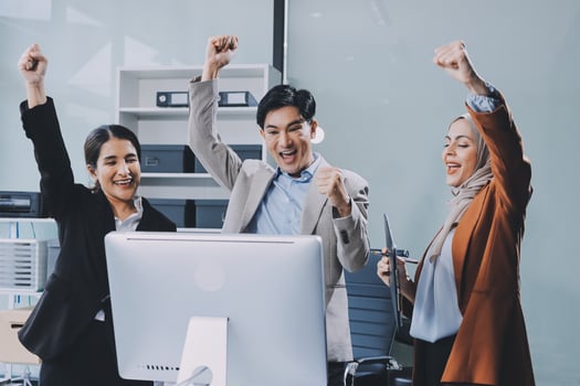 Three business people celebrating in front of a computer photo