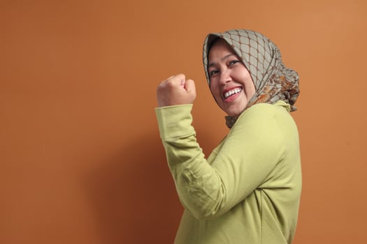Confident muslim woman flexing arm and smiling showing strong energy photo