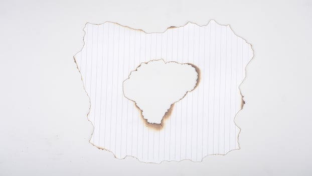 Hole in the burned stripped paper isolated on white background photo