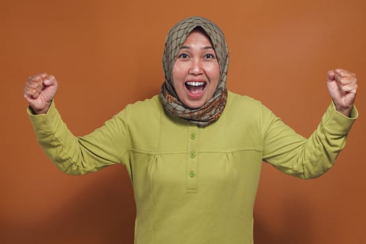 Excited muslim woman cheering with joy, motivation, fist raised high photo