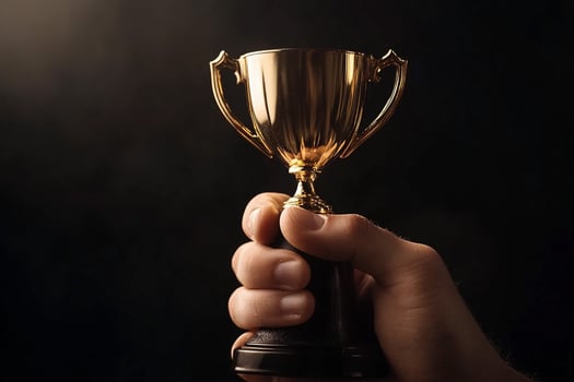 A person holding up a gold trophy on a black background photo