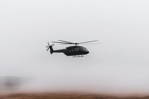A helicopter flying through the fog on a mountain photo