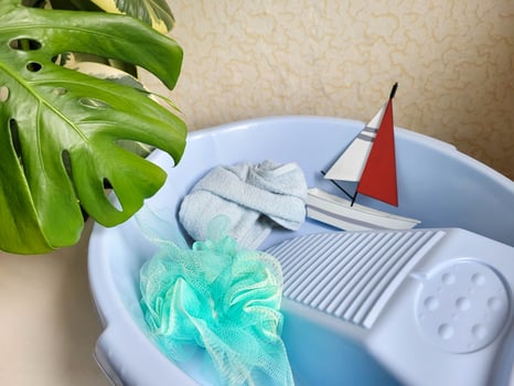 A blue basin, a yacht toy and personal hygiene supplies, a washcloth and a towel. The concept of body care. photo