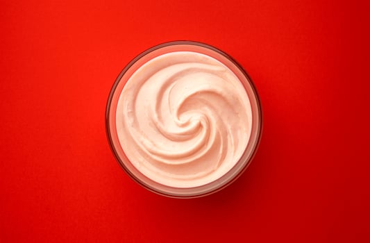 Bowl of strawberry yogurt on red background, top view photo