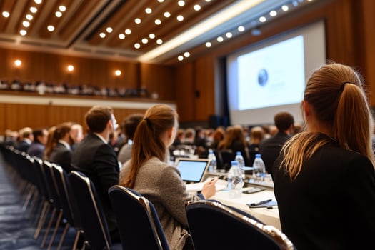 A group of people sitting at tables in a conference room photo
