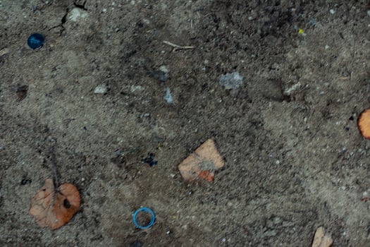 Textured soil with scattered debris, dried leaves and small brick remnants photo