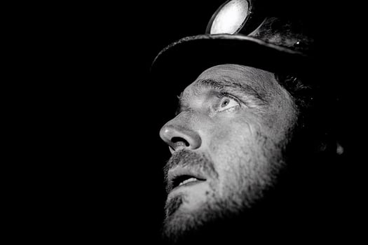 A black and white photo of a man with a light on his face