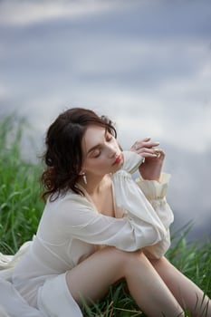 Beautiful young woman in white dress resting on shore lake pond river. Professional makeup and hairstyle with curled hair 1 photo