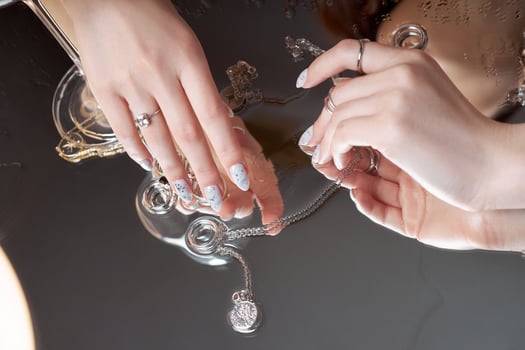 Woman holds rings and a chain with a pendant in her hands. Beautiful manicure on the nails of the hands photo