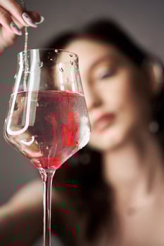 Drops of red blood paint in a glass of water woman looks at the glass. photo