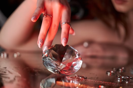 Beauty Woman holds big diamond in hand while lying on table Beautiful hands, professional manicure, large brilliant photo