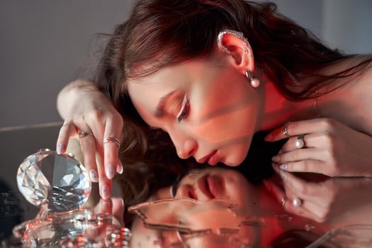 Art beautiful woman with creative makeup is lying on mirror. Beauty portrait of a romantic woman with jewelry photo