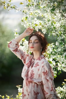 Beautiful romantic woman stands in branches of blooming apple tree. Spring portrait girl in flowers apple tree 1 photo
