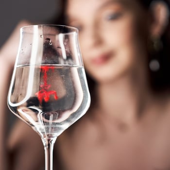 Drops of red blood paint in a glass of water, woman looks at the glass. photo