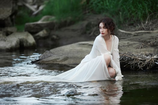 Erotic young woman in a long white dress walks in a spring park near river. Sexy brunette posing in nature 2 photo