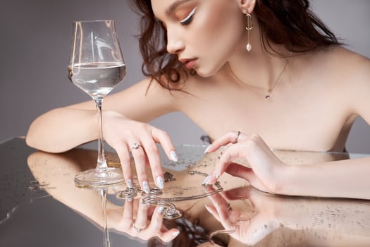 Beauty portrait of a woman with glass in hand rings are on the mirror table. Natural cosmetics photo