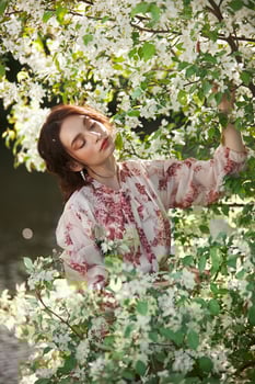 Beautiful romantic woman stands in branches of blooming apple tree Spring portrait girl flowers apple tree photo