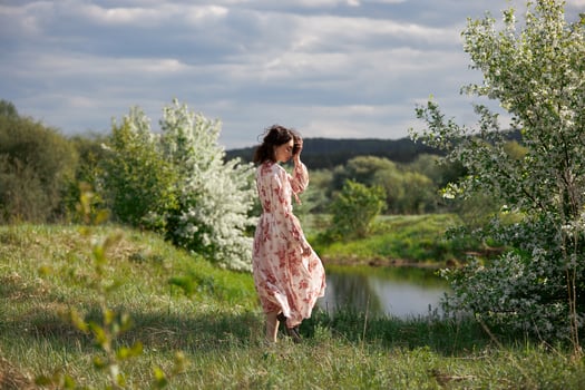 Young woman in long dress walks in spring garden near lake. Girl is resting in nature spring has come.. photo