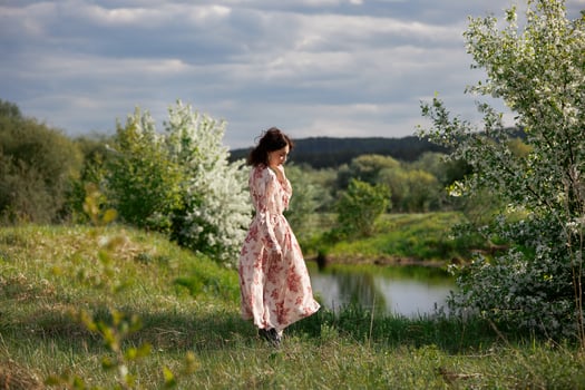 Young woman in long dress walks in spring garden near lake. Girl is resting in nature, spring has come.. photo