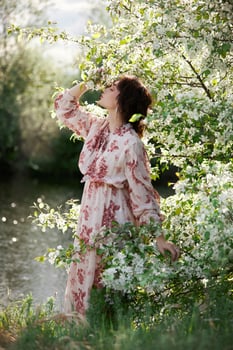 Beautiful romantic woman stands in branches of blooming apple tree. Spring portrait girl in flowers apple tree. photo