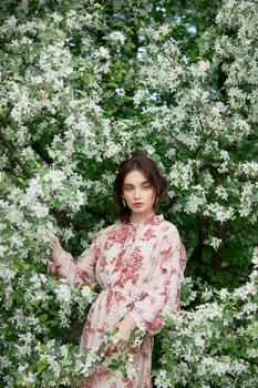 Woman with natural makeup, floral cosmetics for skin of the face, girl posing in flower branches of blooming apple tree in spring. photo