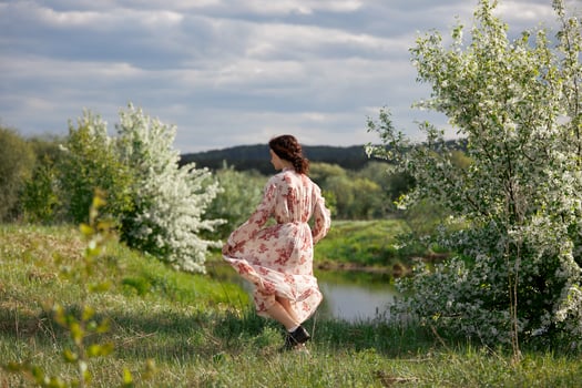 Young woman in long dress walks in spring garden near lake. Girl is resting in nature, spring has come. photo