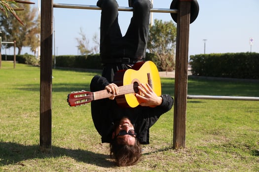 Young Man Plays Guitar Music Hanging Upside Down In Park photo