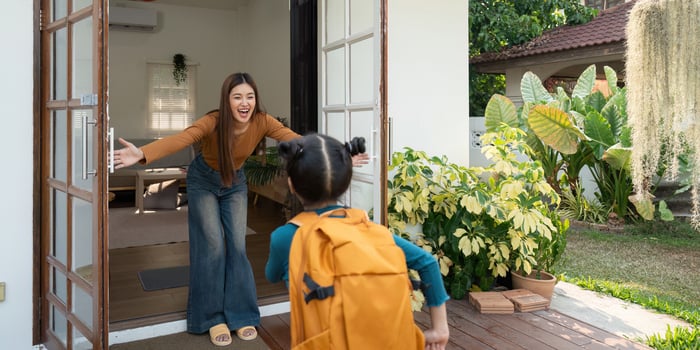 Joyful Reunion After School. A mother embraces her daughter upon her return home. photo