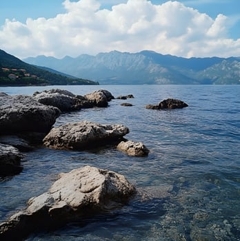 A body of water with rocks and mountains in the background photo