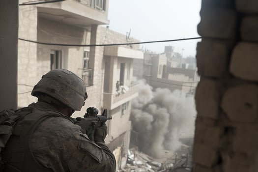 A soldier is looking out a window at a building photo