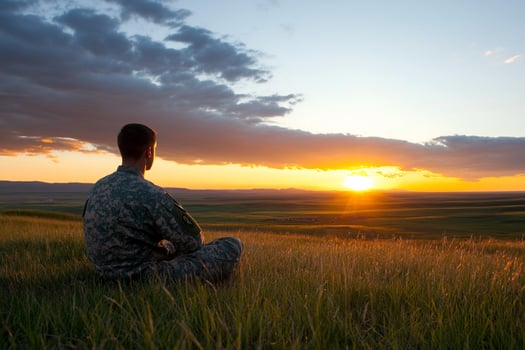 A soldier sitting in the grass at sunset photo