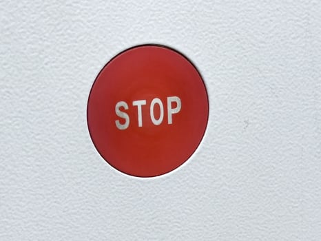 Red stop button on white textured surface for emergency use photo