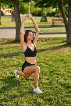 Exercises, in ,the park at sunny daytime. Beautiful young woman in sportive clothes photo