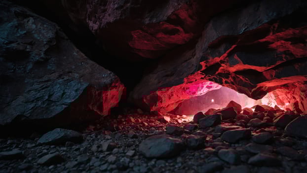 A cave entrance illuminated by colorful lights, revealing scattered rocks inside. photo