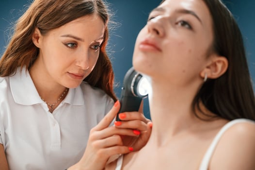 Beauty salon ,worker ,is examining, skin of the woman by using a device with light and lens photo