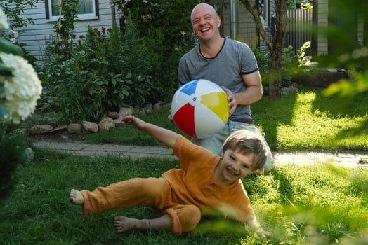 Summer family outdoor activities. Father and small son having fun playing with beach ball in backyard. photo