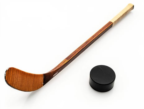 Wooden hockey stick and black puck on a white background photo