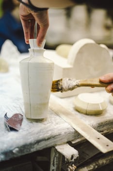 A skilled artisan carefully applies glaze to a ceramic vase photo