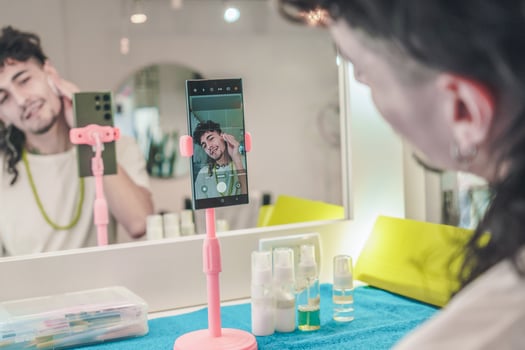 Hairdresser recording makeup tutorial with smartphone on tripod in beauty salon photo