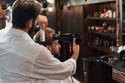 Using hair dryer. Man is visiting, modern barber shop. Modern style photo