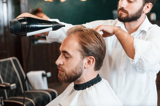 Using hair, dryer. Man is visiting modern barber shop. Modern style photo